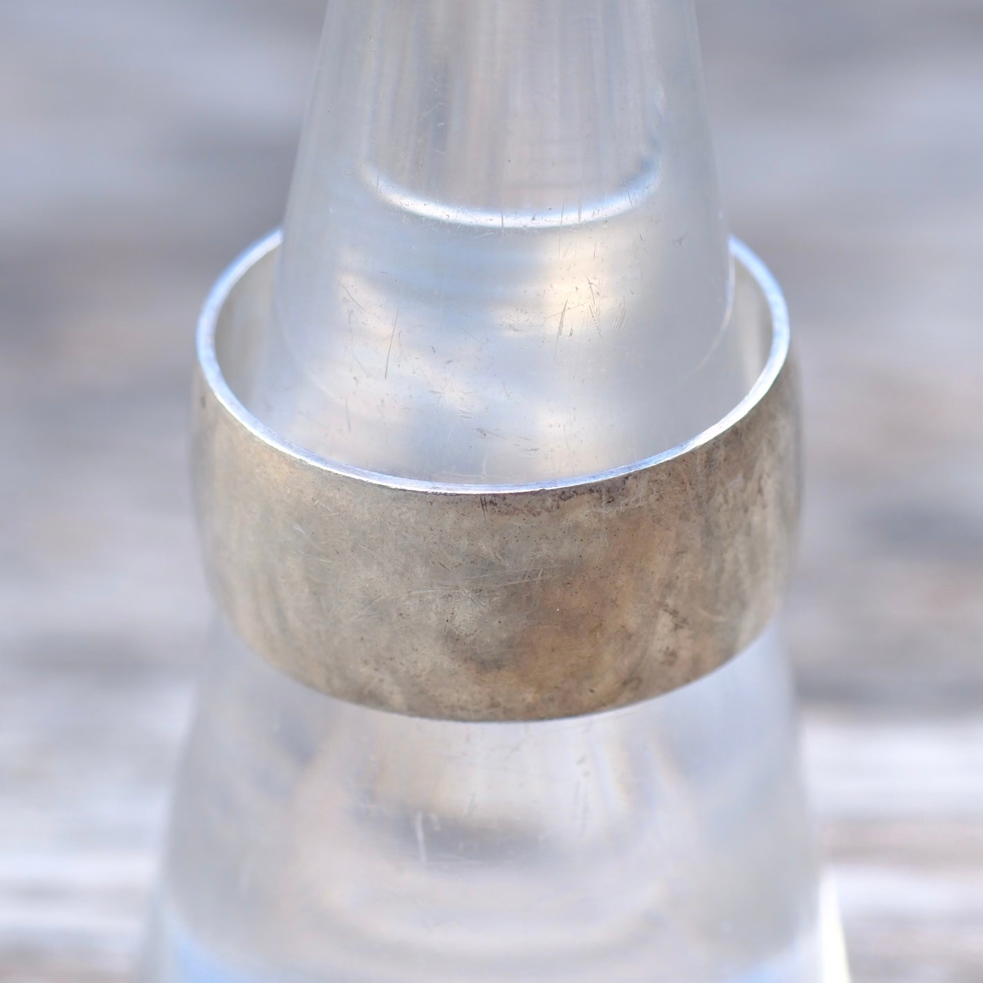 Silver ring on a clear glass stand with a blurred background
