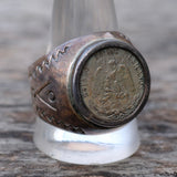 Silver ring with a coin inset on a wooden surface