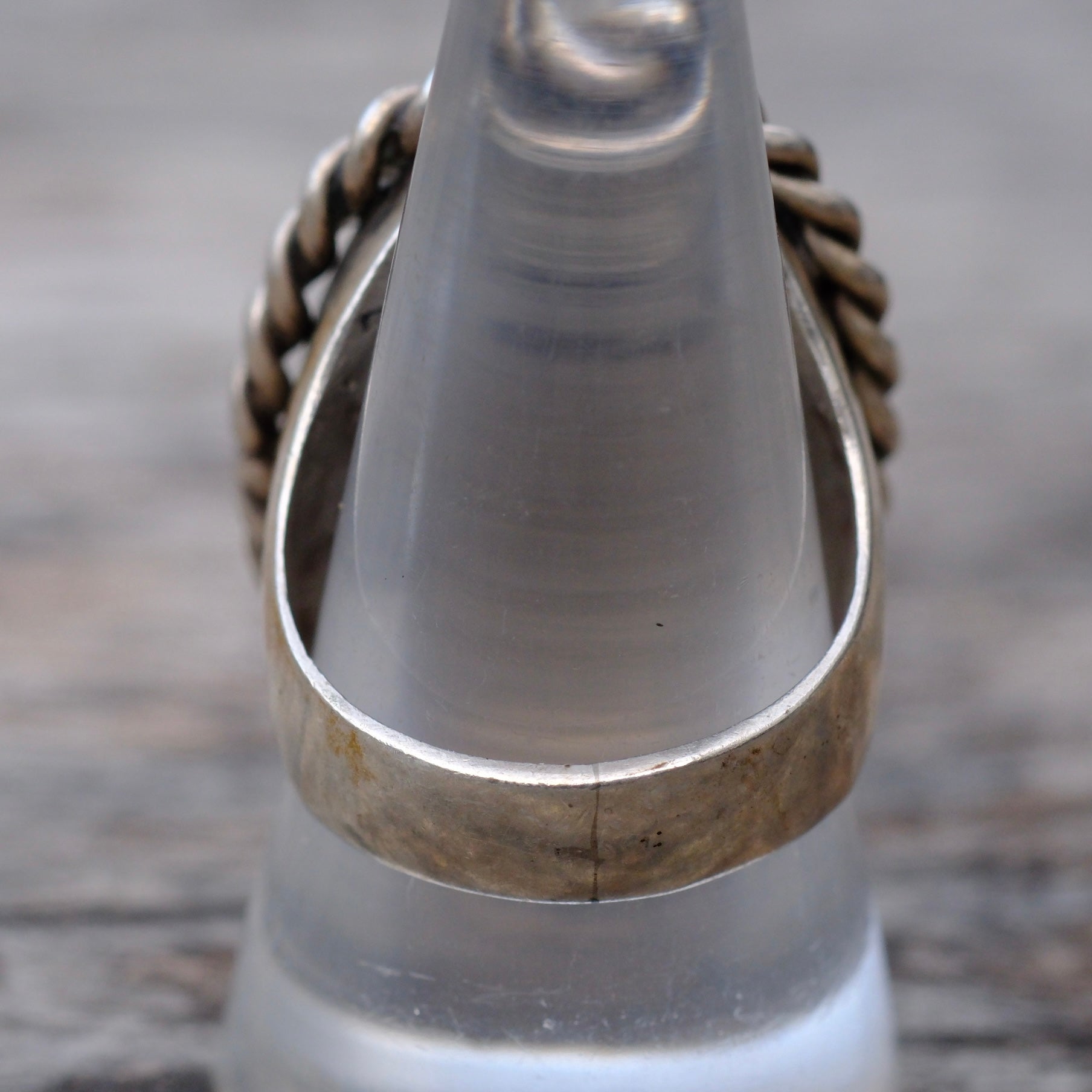 Close-up of a metallic ring with a textured band on a wooden surface