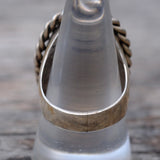 Close-up of a metallic ring with a textured band on a wooden surface