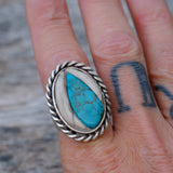 Silver ring with a turquoise stone on a person's finger