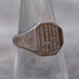 Close-up of a metallic ring with '28' engraving on a blurred background
