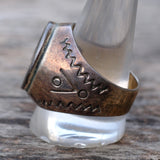Silver ring with intricate design on a wooden surface