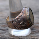 Silver ring with intricate designs on a wooden surface