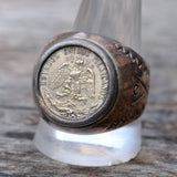Silver ring with a Mexican coin design on a wooden surface